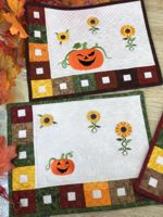 Quilted placemats with embroidery of pumpkins and sunflowers.