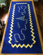 Roayl blue quilted tablerunner with golden border and embroidery of music notes.
