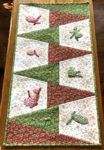 Quilted tablerunner with one-color pine cone embroidery.