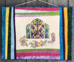 Easter-themed quilt with embroidery of a church window, flowers and multi-colored borders.