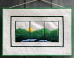 A small wall quilt with embroidered mountain landscape.