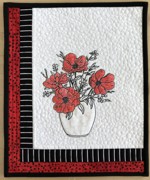 Small black-and-red quilt with a bouquet of poppies embroidered in the center.