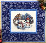 Small wall quilt with embroidery of snowmen in the center and blue borders.