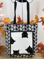 Black-and-white tote with spooky cats embroidery on the front panel.