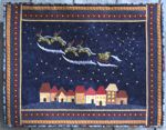 A dark blue wall quilt with embroidered Santa's sleigh in the sky over applique houses