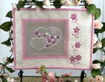 Light-colored small quilt with hearts and flower embroidery