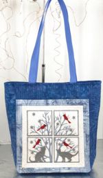 Quilted blue tote bag with embroidery on the front panel.