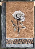 a small wall quilt with a rose embroidery