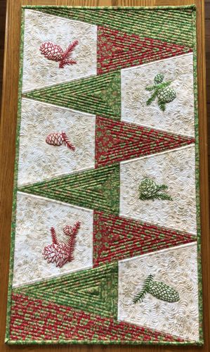 Finished tablerunner with pine cone embroidery on a tablerunner.