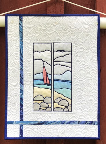 A small quilt with an embroidered one-color seascape, colored then with inktense blocks