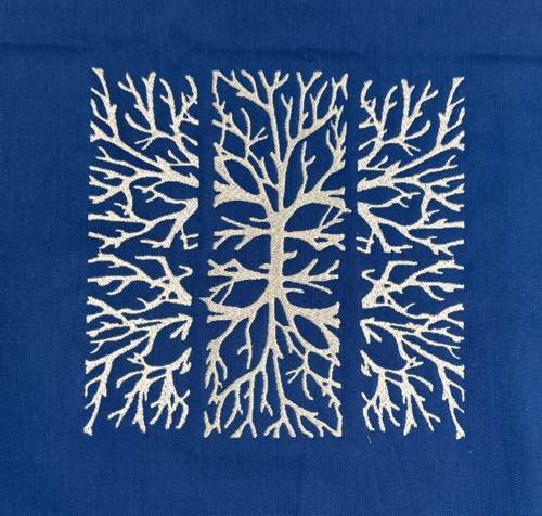 Stitch-out of the tree branches designs on the blue background.