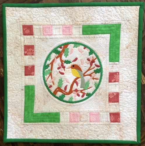 A quilt with embroidery of spring branches in the center.