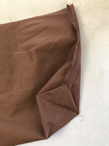 Fold the corners to the side seams and stitch them to the side seams by hand.