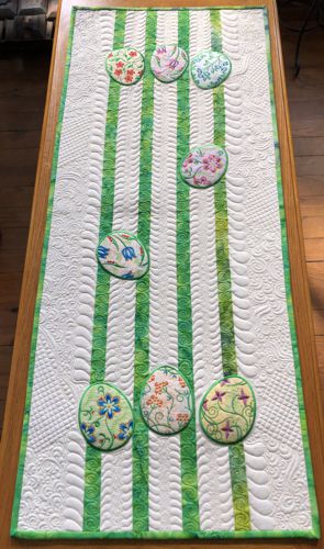 Light-colored Easter-themed tablerunner with applique egg embroidery.