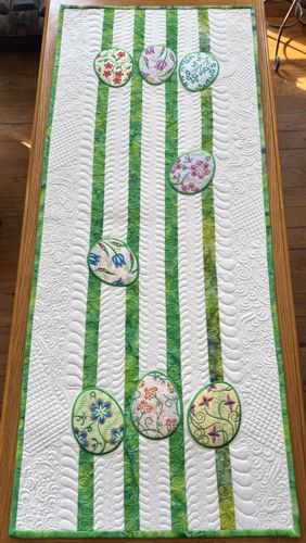 Light-colored Easter-themed tablerunner with applique egg embroidery.