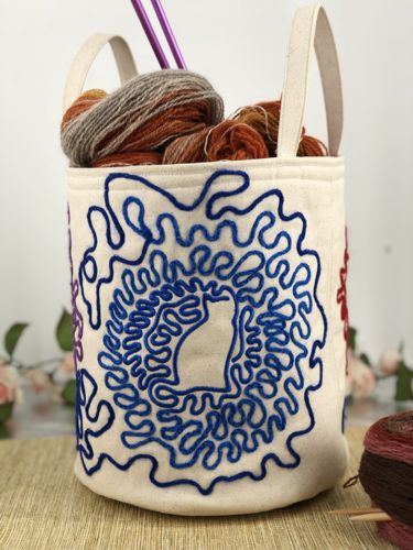 Finished round basket with embroidery of cat silhouettes tangled in yarn