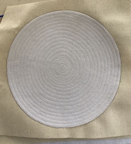 The felt circle is stitched to the canvas.